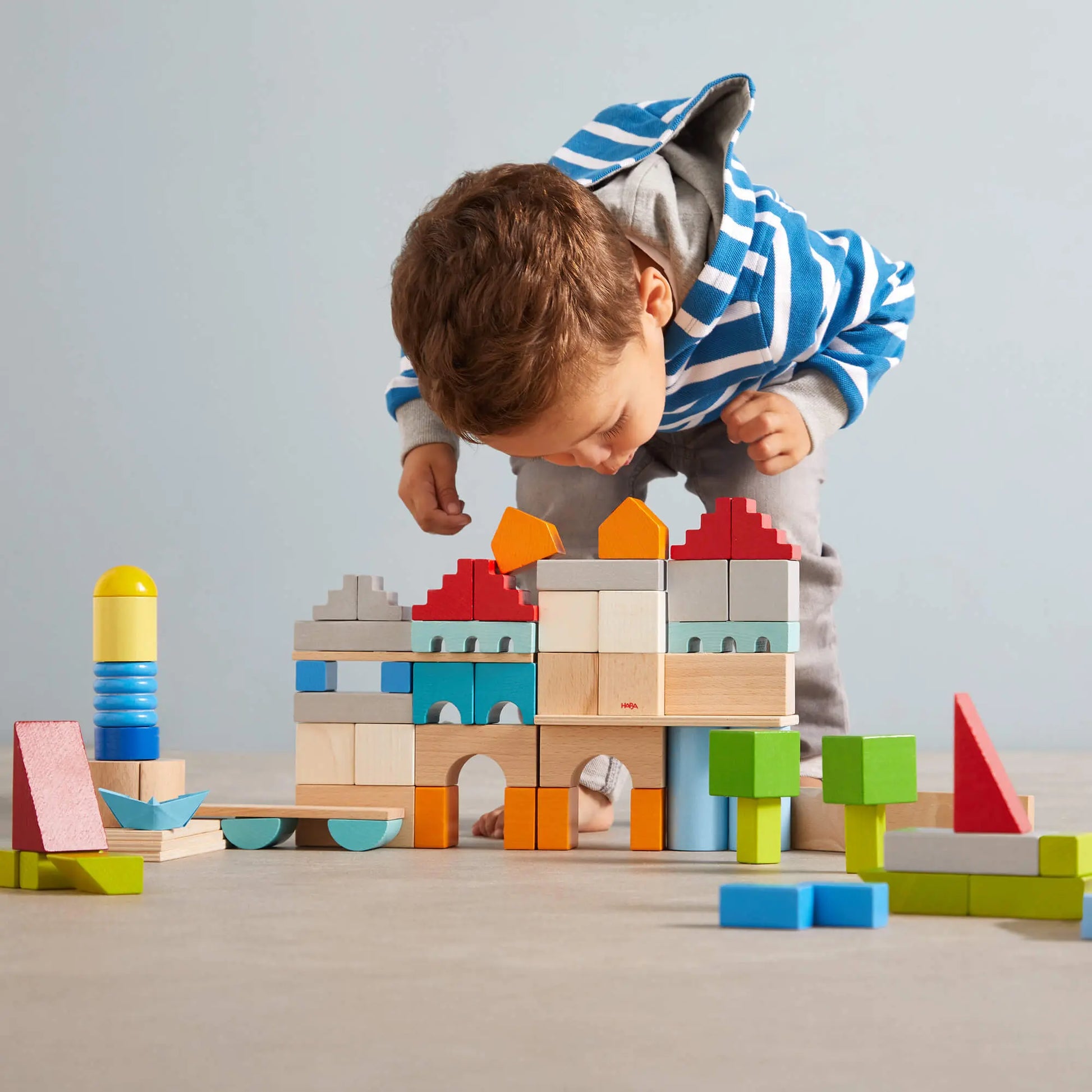 Child playing with colorful building blocks on a light gray background