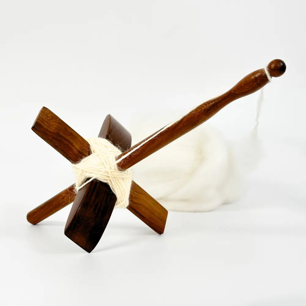 Wooden yarn swift with a ball of white yarn on a white background