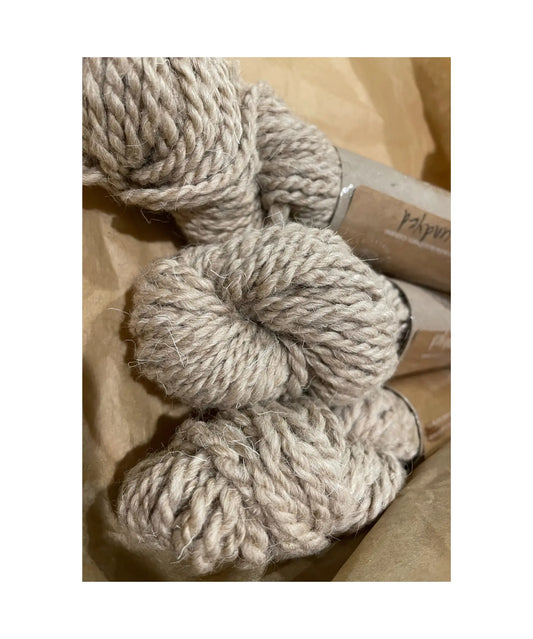 Three skeins of beige yarn on a wooden surface