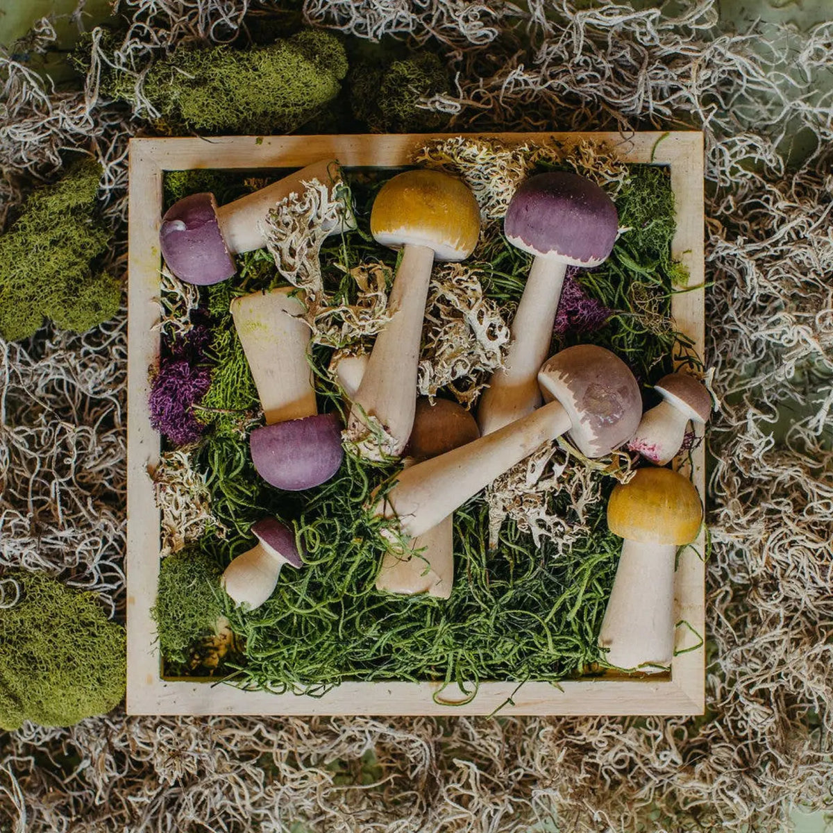 Painted wooden mushrooms arranged with moss for a seasonal nature table display
