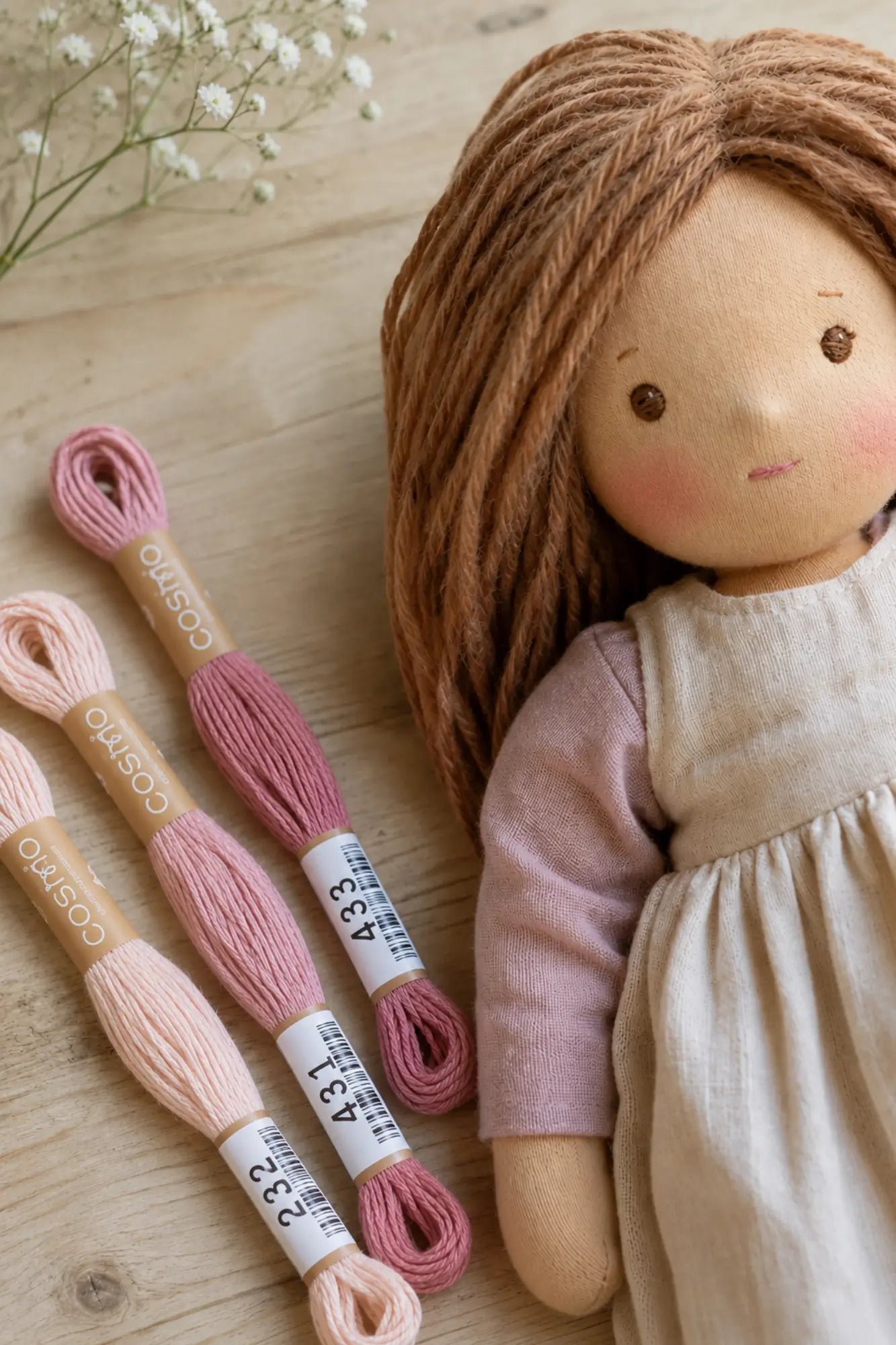 Waldorf doll with pink lips using pink floss next to her lifestyle scene