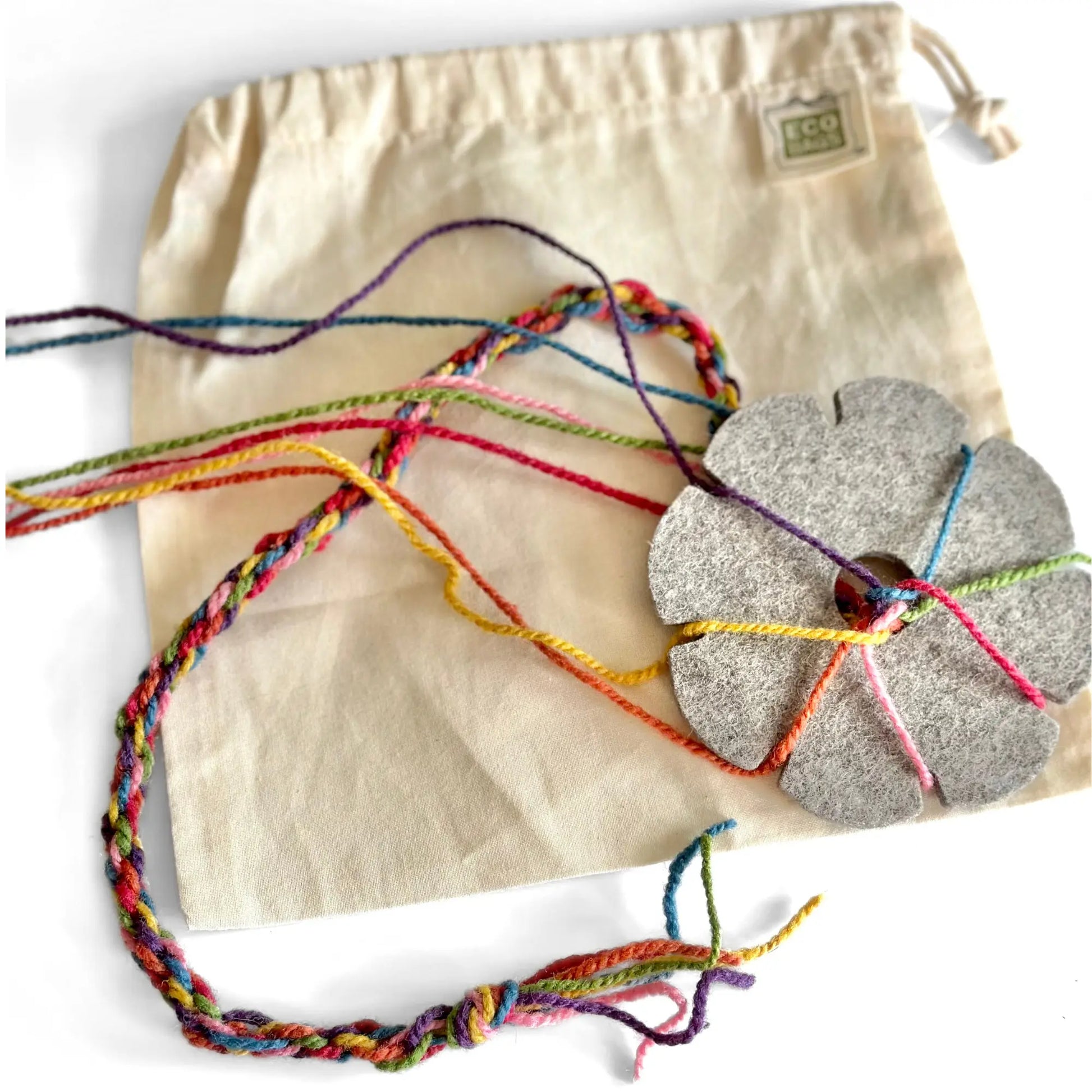 Wool Felt Kumihimo Braiding Felt Flower with rainbow yarn cord on a cotton drawstring bag