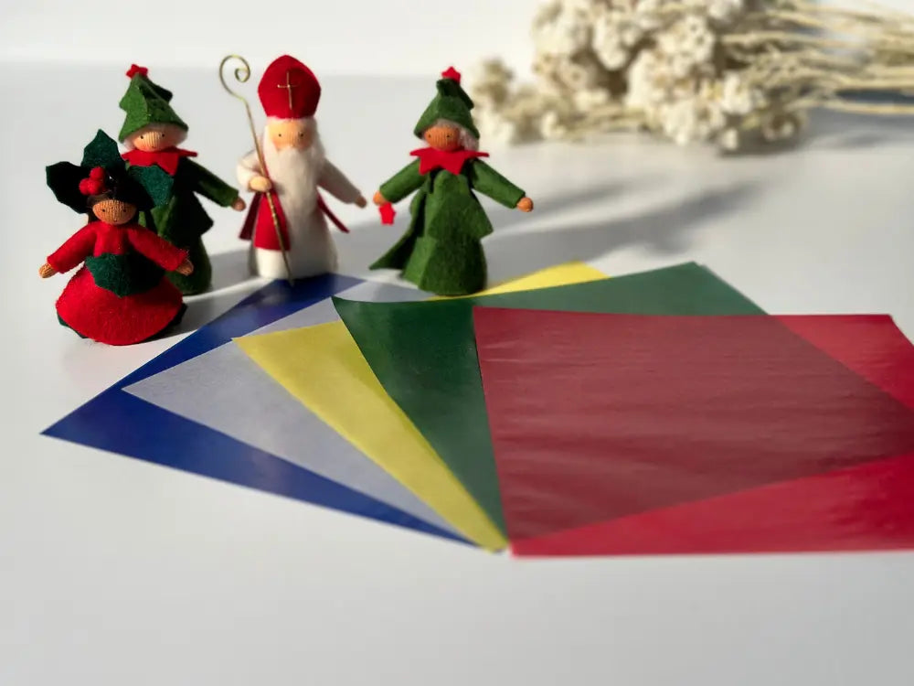 holiday kite paper fanned out with St. Nicholas, poinsettia, and christmas tree fairy dolls on white
