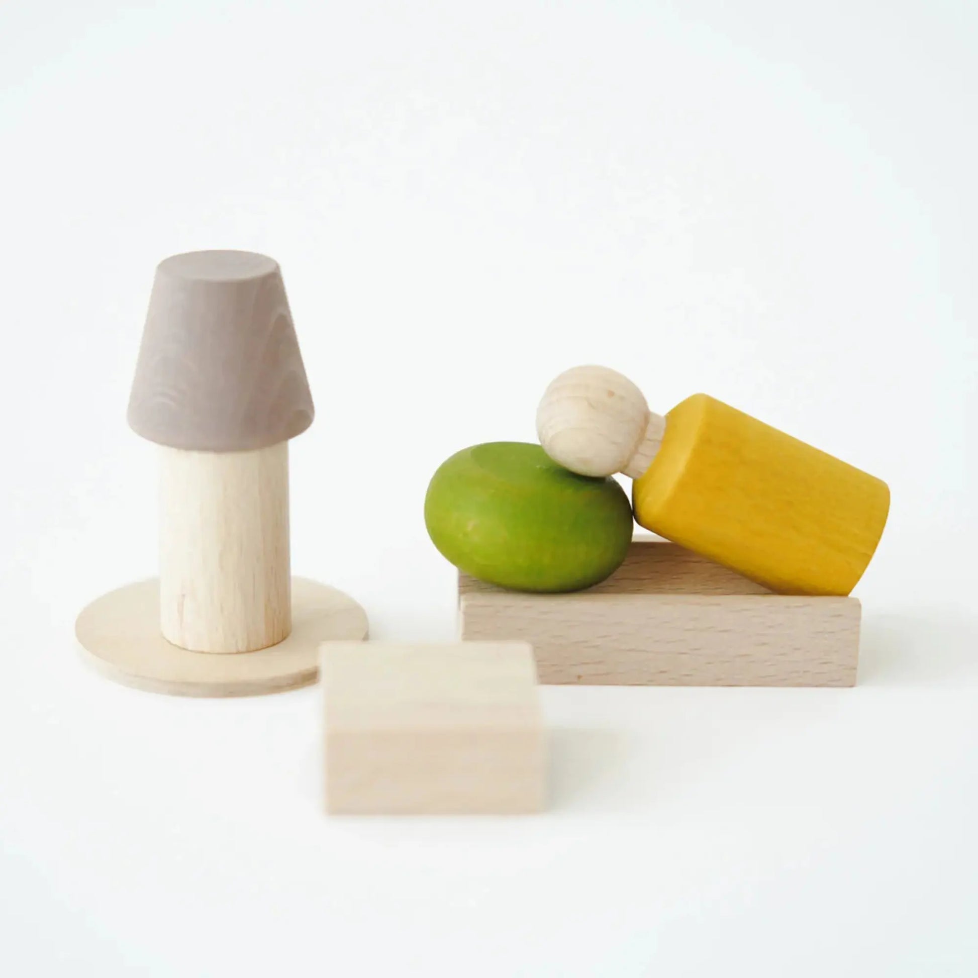 Set of wooden toys including a gray cone, green sphere, yellow block, and beige cube on a white background.