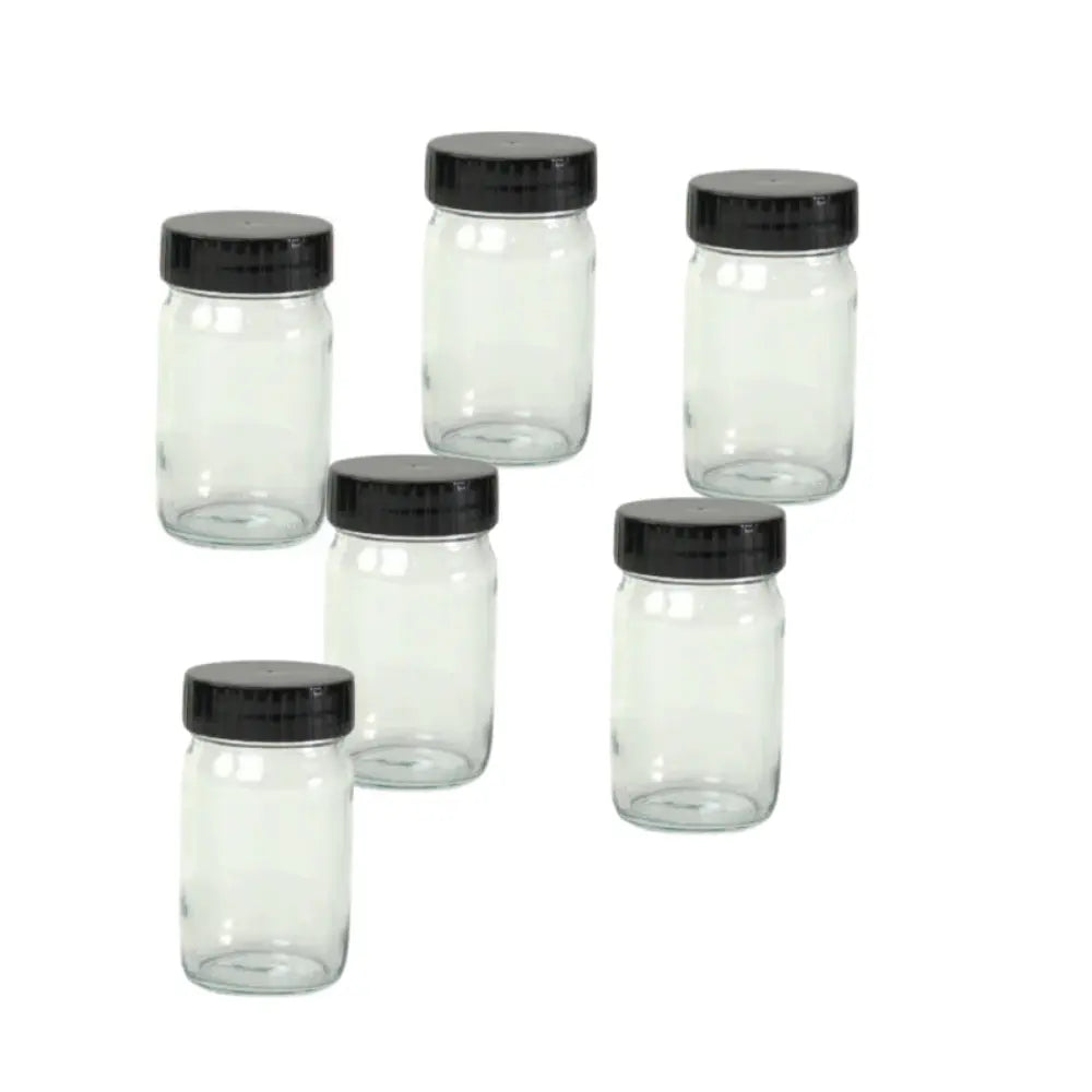 Set of six clear glass jars with black lids on a white background