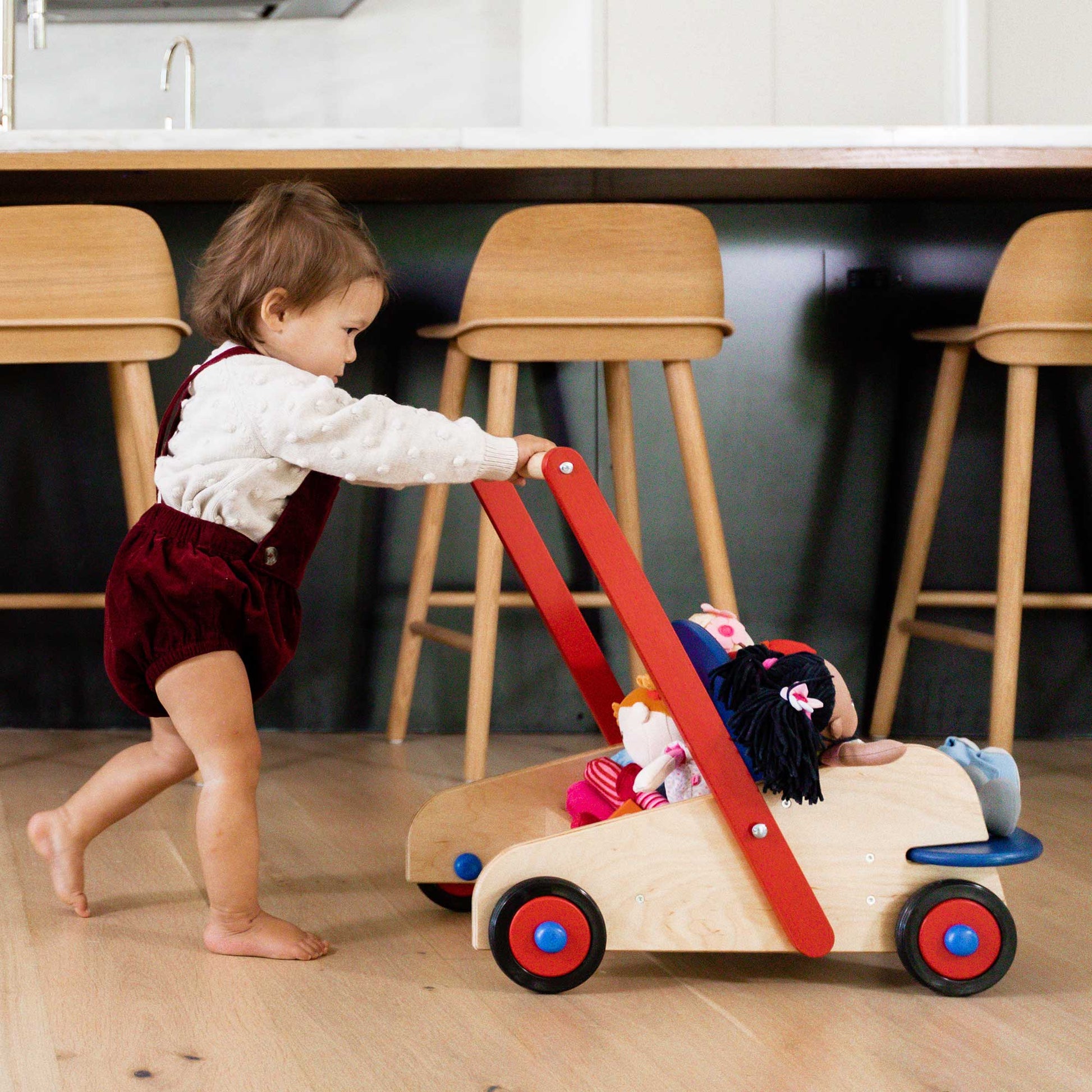 Child playing with a wooden toy car in a kitchen