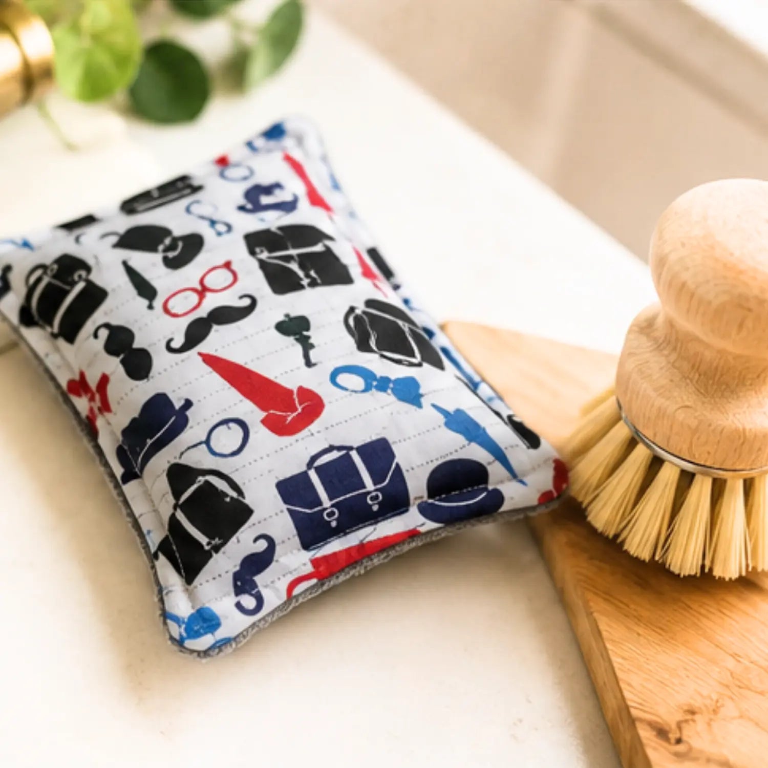 British print washable sponge beside a sink, bowl, and wooden dish brush
