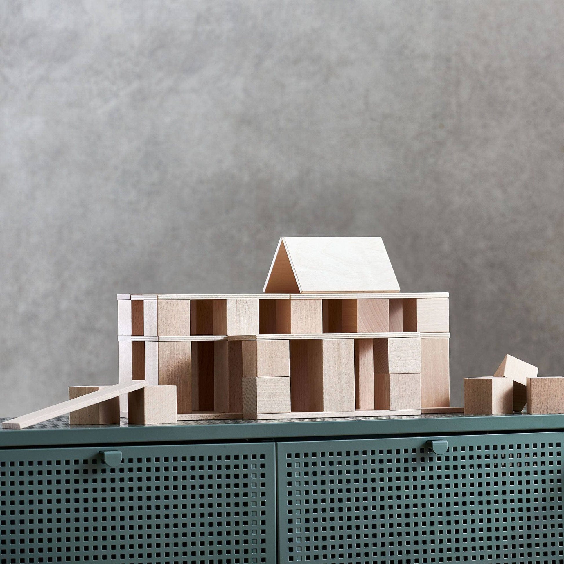 Wooden building blocks arranged into a house structure with layered baseplates and cubes
