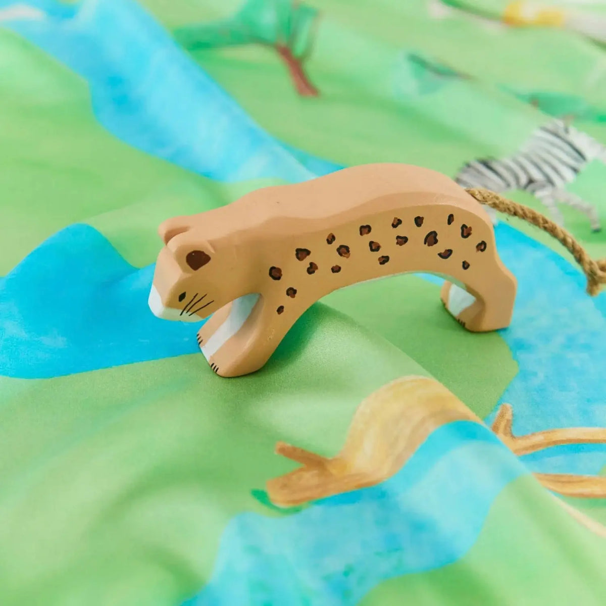 Sarah’s Silks hand-painted wooden cheetah toy on a colorful playsilk background