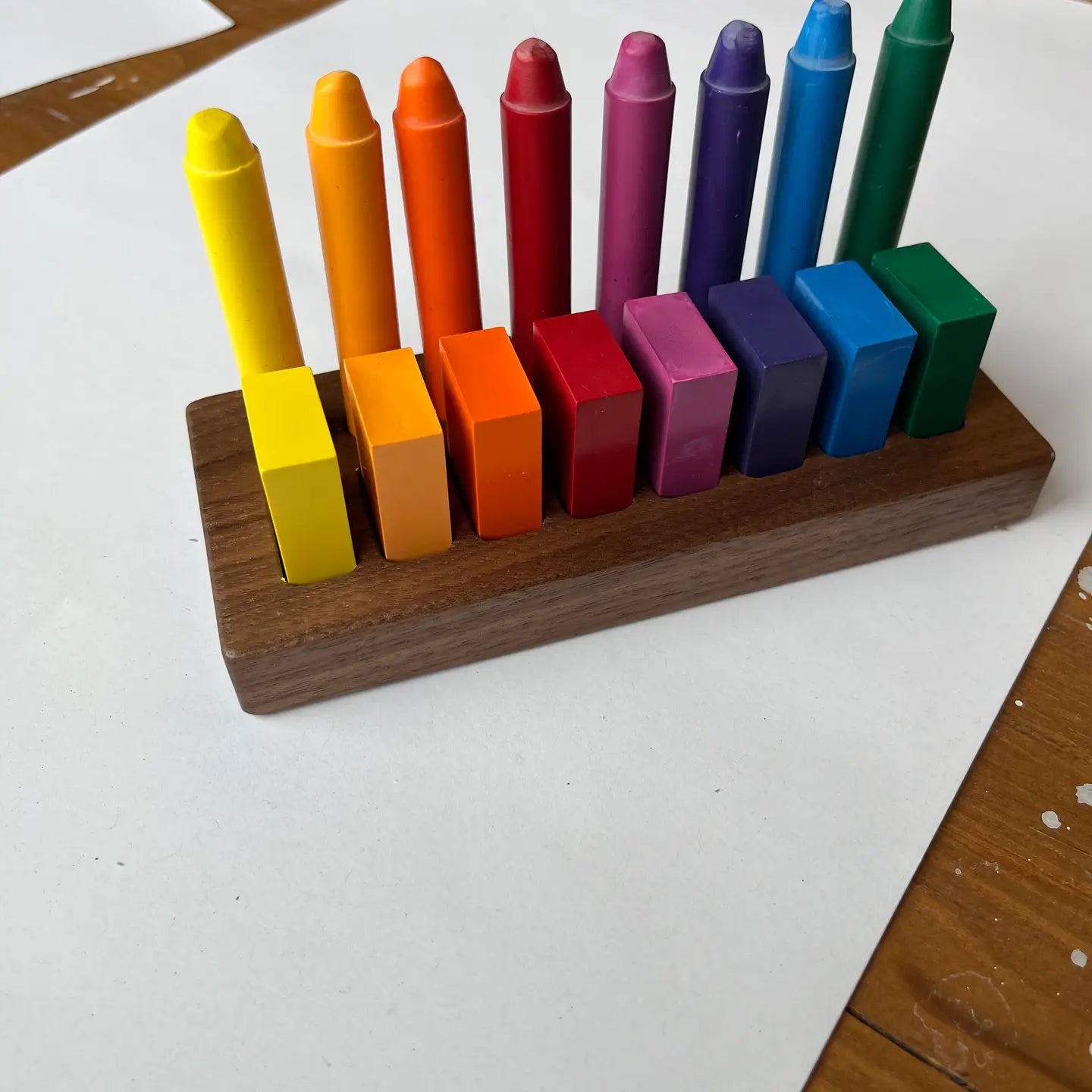 Set of colorful crayons in a wooden holder on a white surface