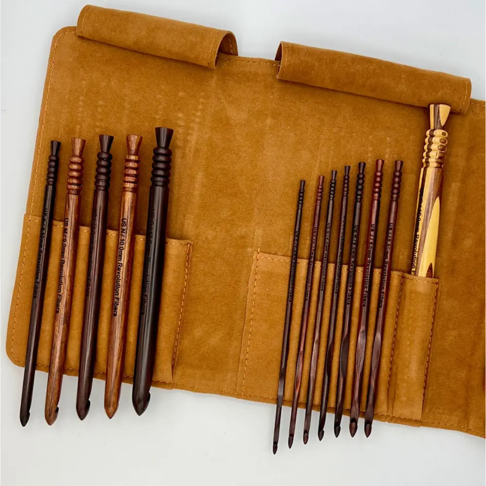 Set of wooden crochet hooks in a brown leather case on a white background