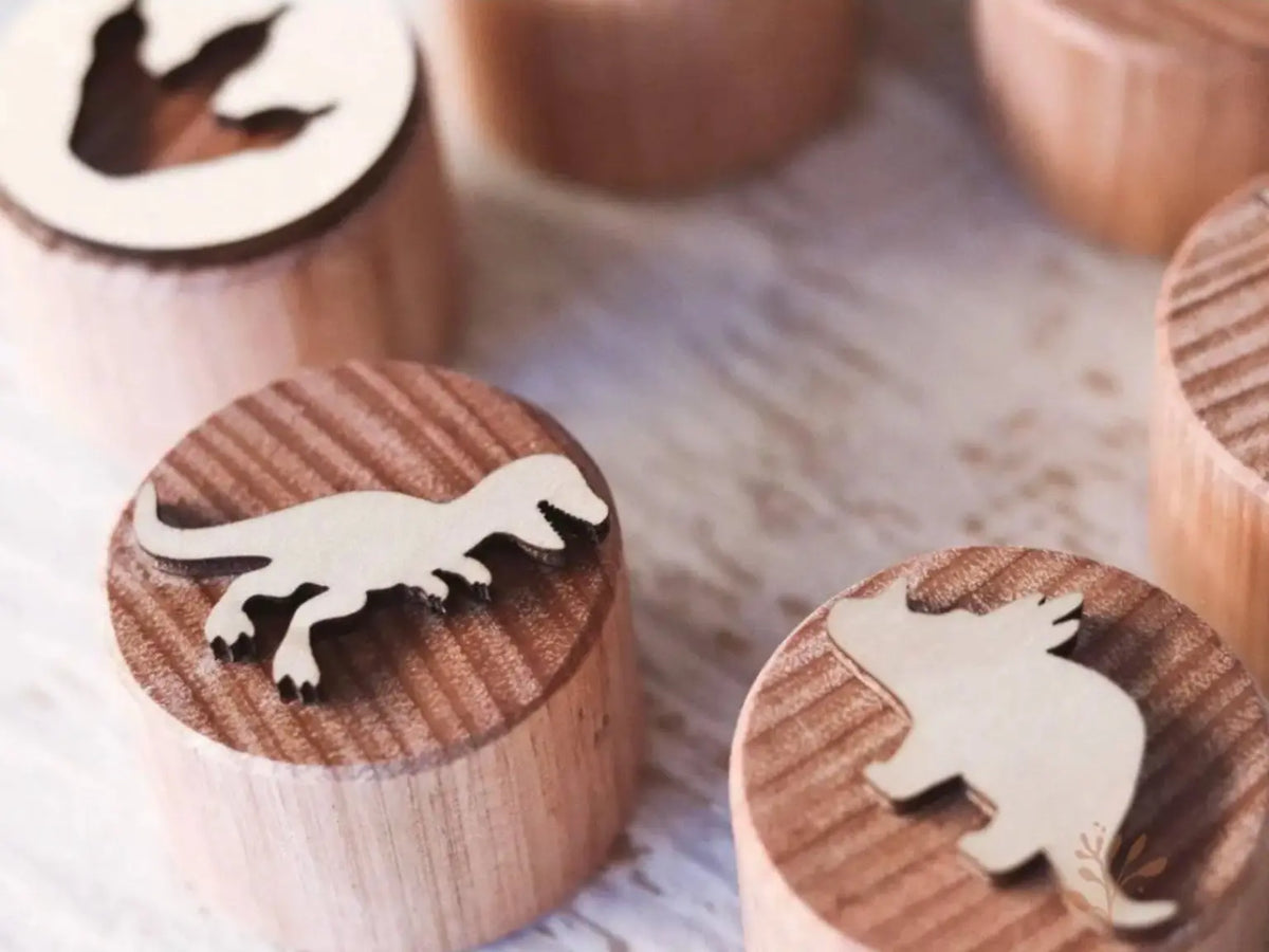 Close-up of wooden dinosaur play dough stamps showing carved dinosaur designs