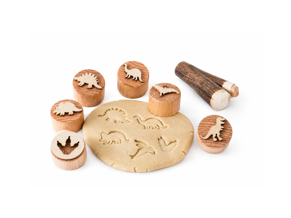 Wooden dinosaur play dough stamp set with natural dough impressions on a white background