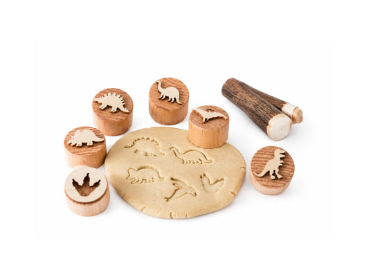 Wooden dinosaur play dough stamp set with natural dough impressions on a white background