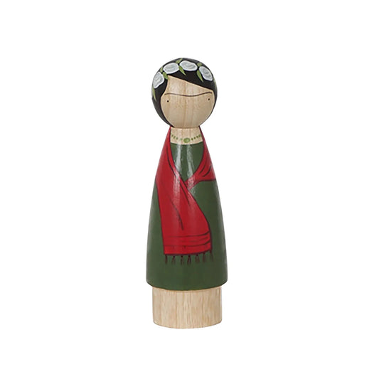 Wooden figurine of a Frida Kahlo with a green dress and red shawl on a white background