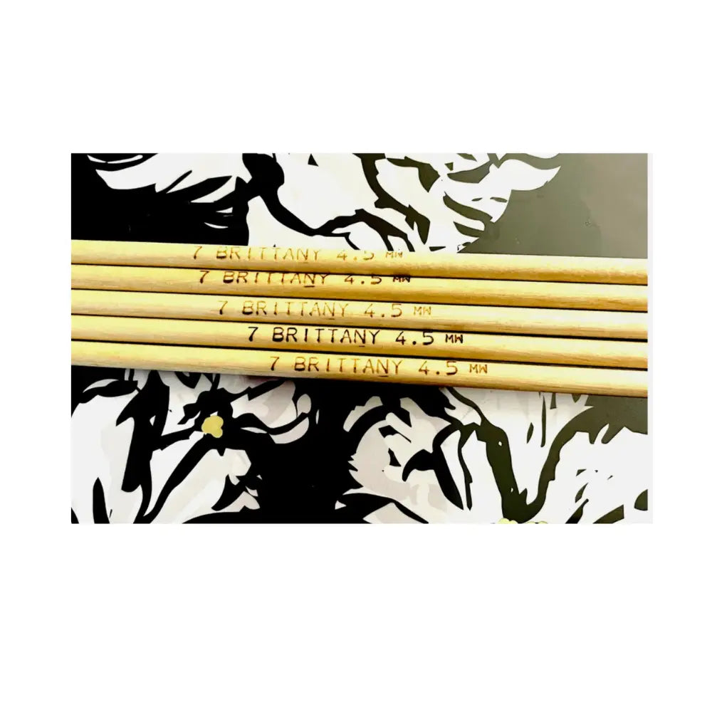 Set of gold pencils with '7 Brittany 4.5 mm' marking on a black and white patterned background