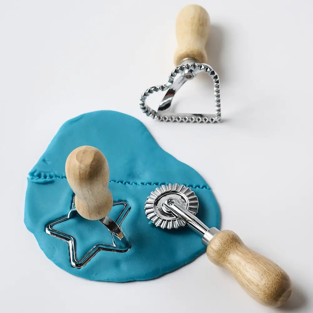 Wooden dough cutters pressing a heart shape and rolling lines into blue play dough