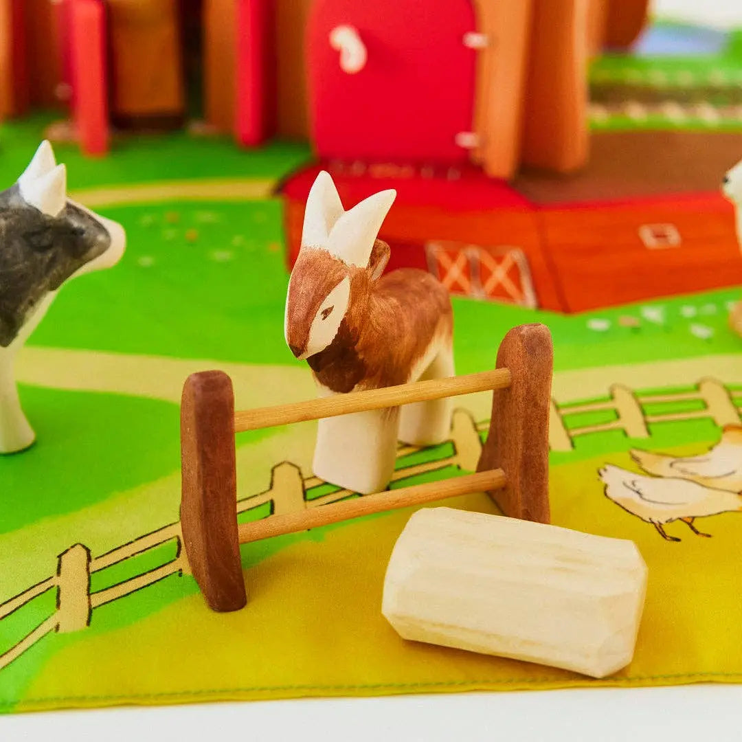 Wooden goat toy in farm scene behind fence for small world farm play and nature table display