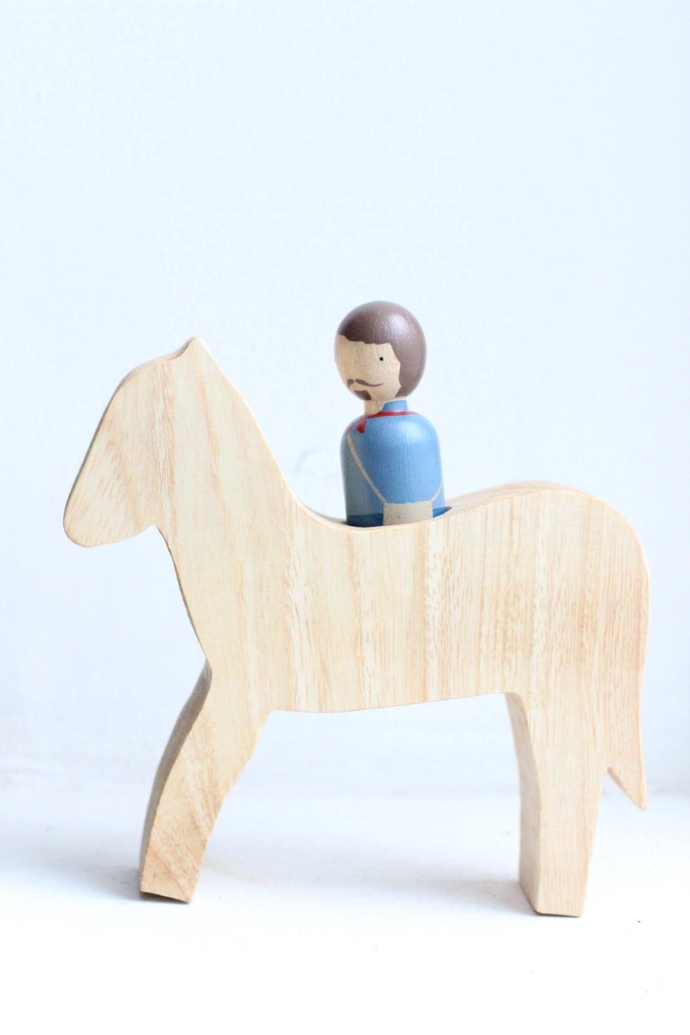 Wooden horse toy with a peg doll rider on a light blue background