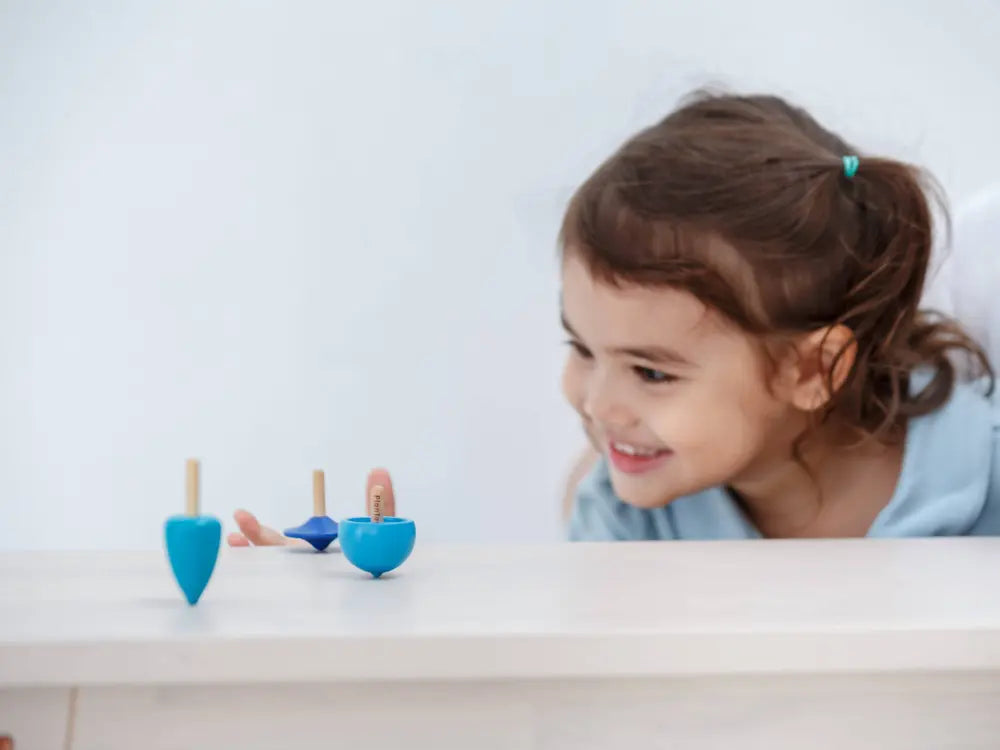Child playing with colorful wooden toys on a white surface