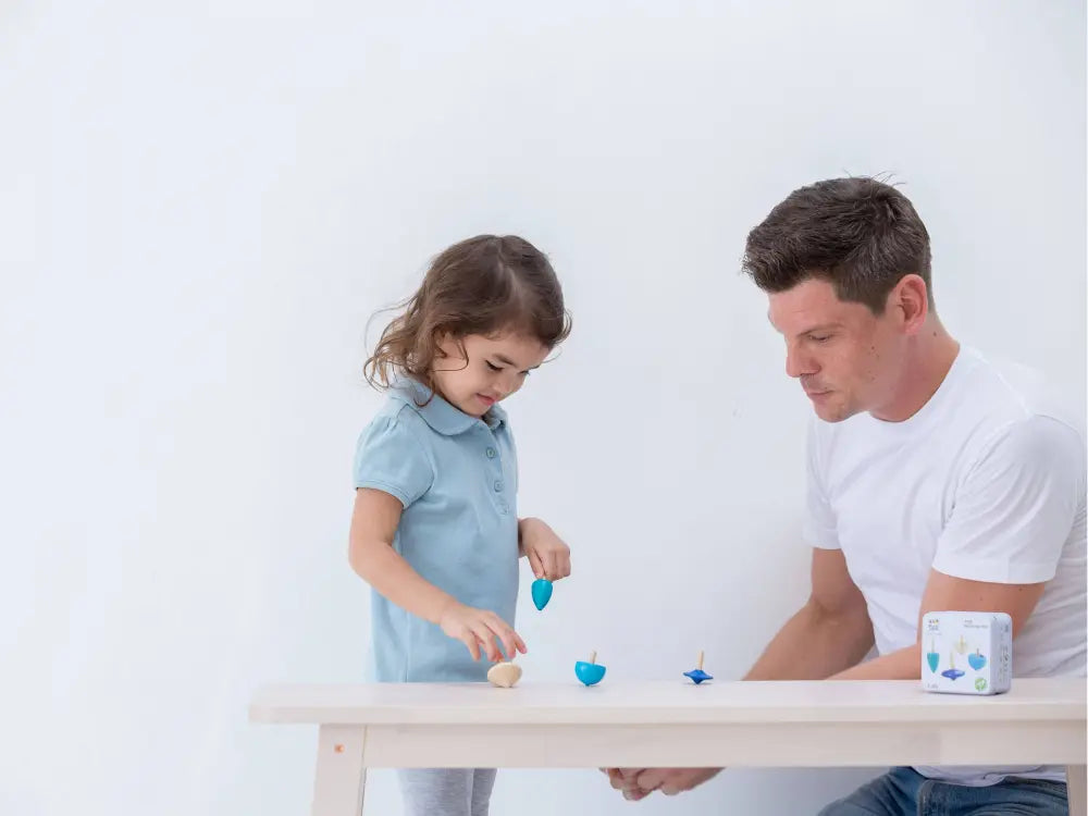 Man and child playing with toys at a table against a white background