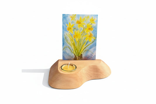 Wooden candle holder with a card featuring a painting of yellow flowers on a wooden surface.