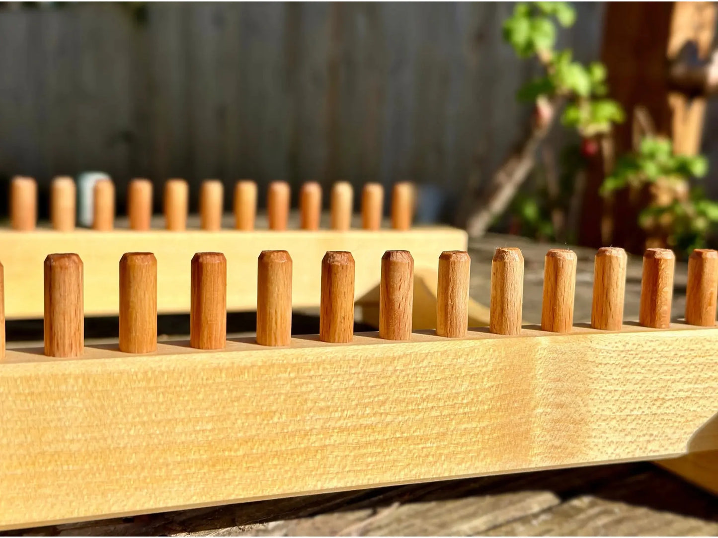 Close-up of solid maple potholder loom with wooden pegs for weaving small textiles