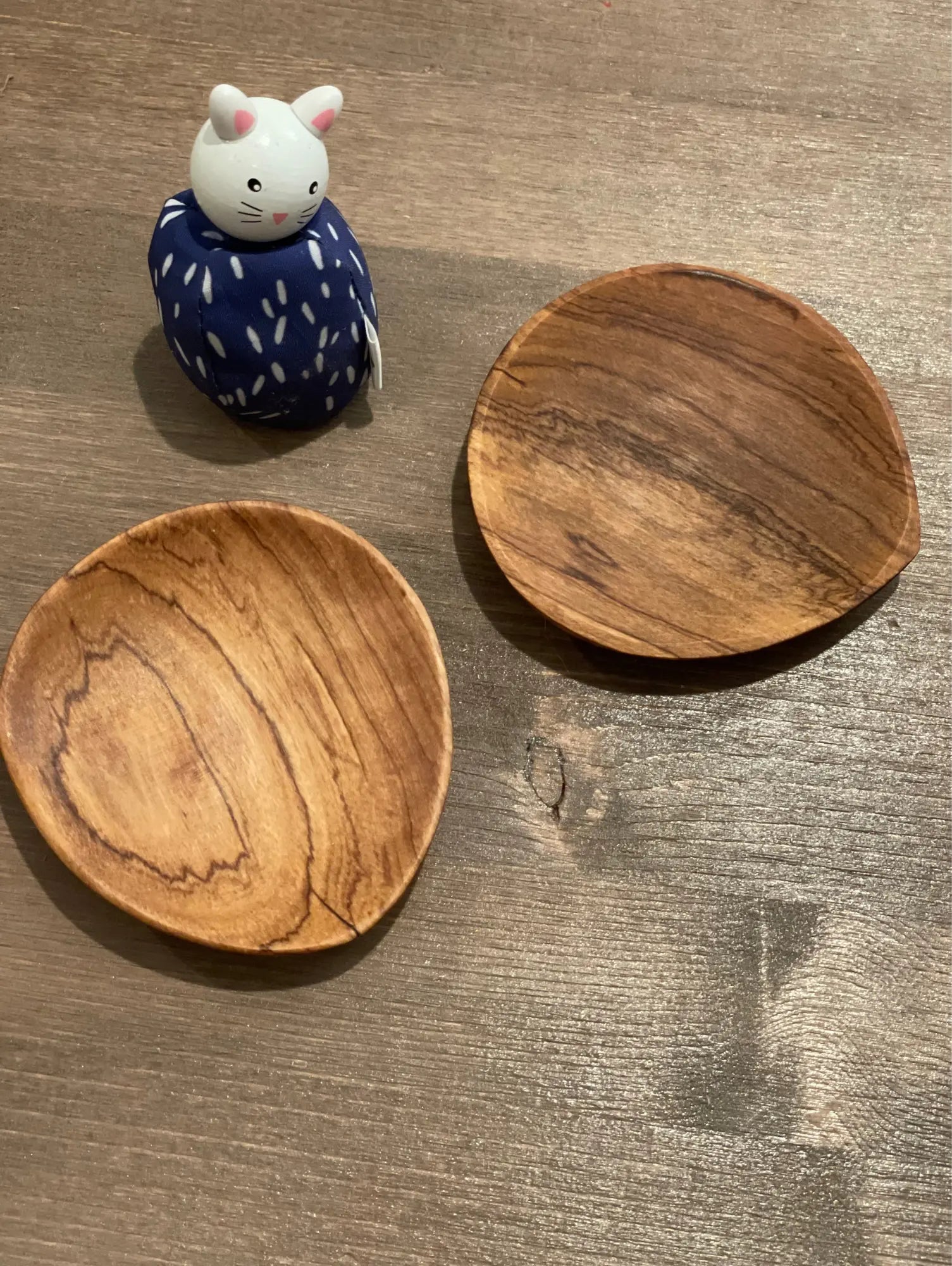 Two olive wood plates and a small figurine on a wooden surface