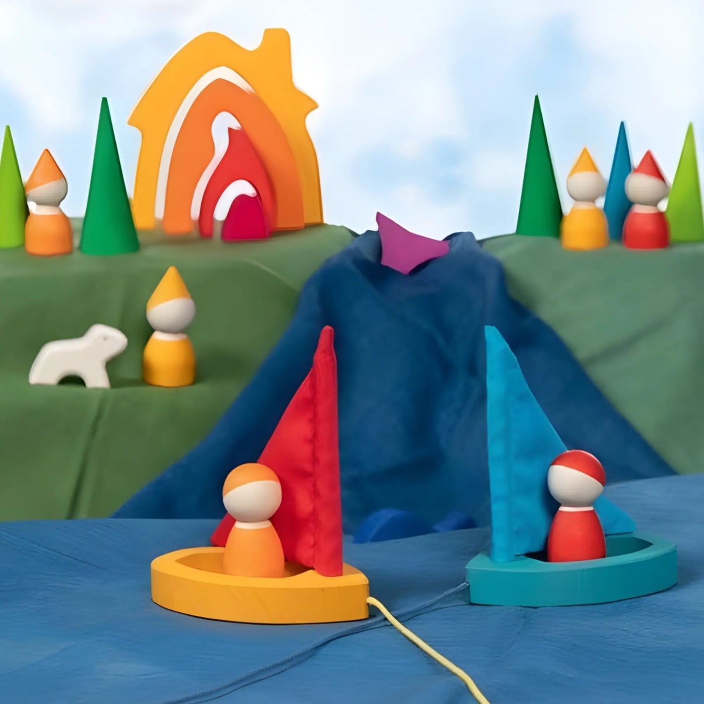 Goki Peg Dolls sitting in toy wooden sailboats with play cloths, gnome peg dolls and a mushroom house in a play scene