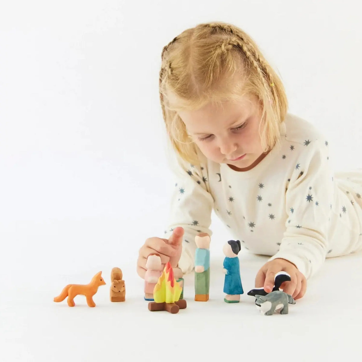 Child playing with a Sarah’s Silks wooden skunk and woodland figures during imaginative small-world play