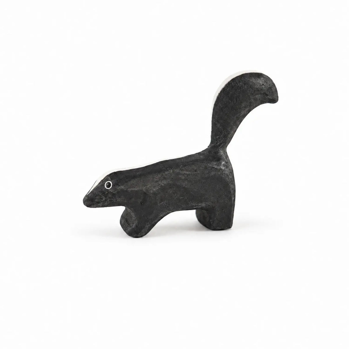 Side view of Sarah’s Silks wooden skunk toy showing its black-and-white markings and curved tail