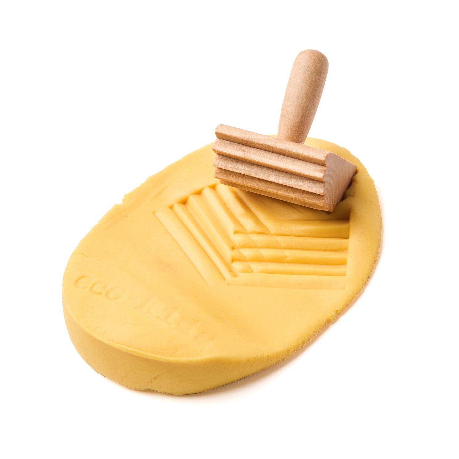 Wooden texture stamp pressing a pattern into natural play dough for sensory play
