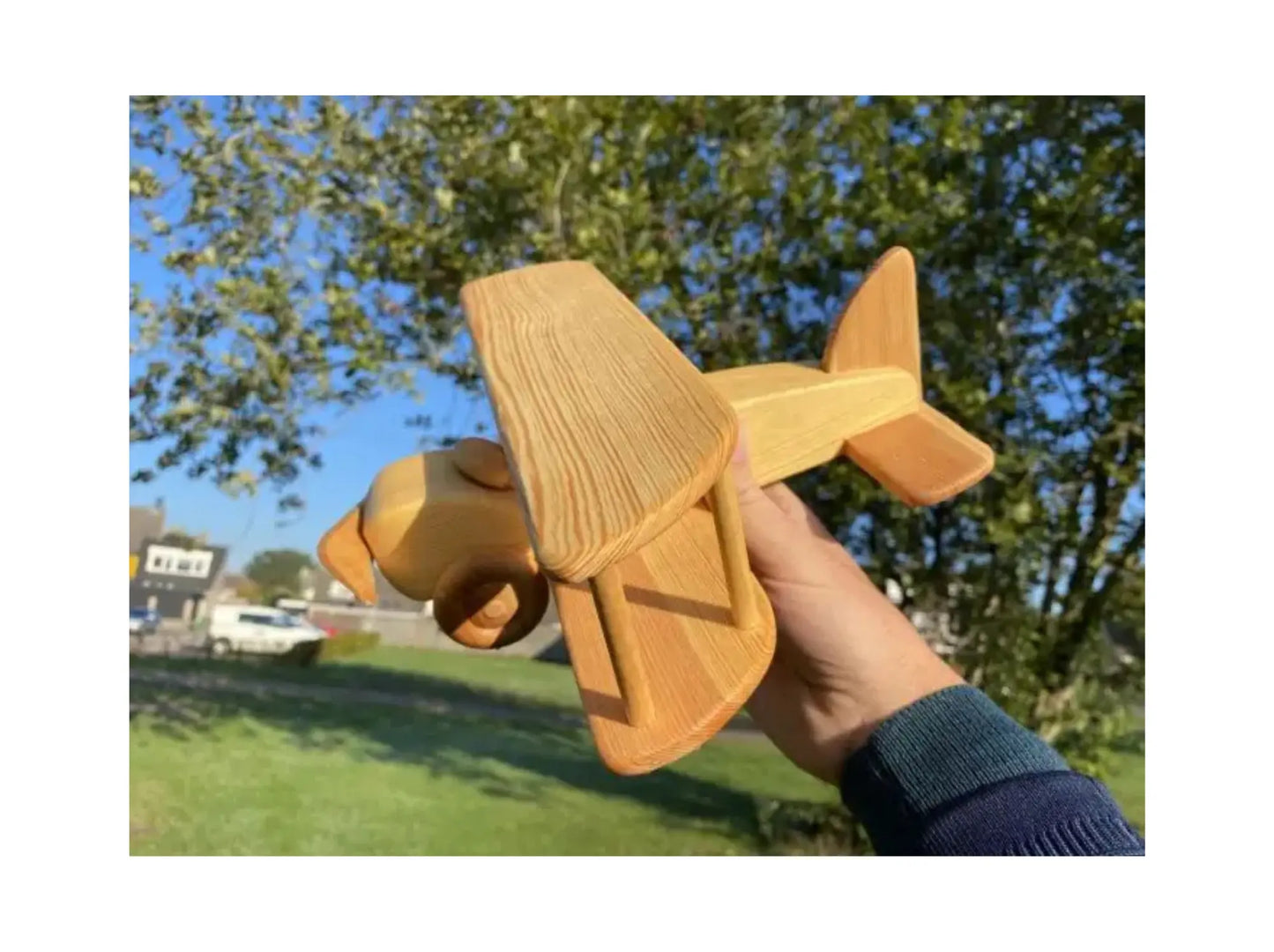 Handcrafted wooden toy airplane made of beechwood held in hand for imaginative play