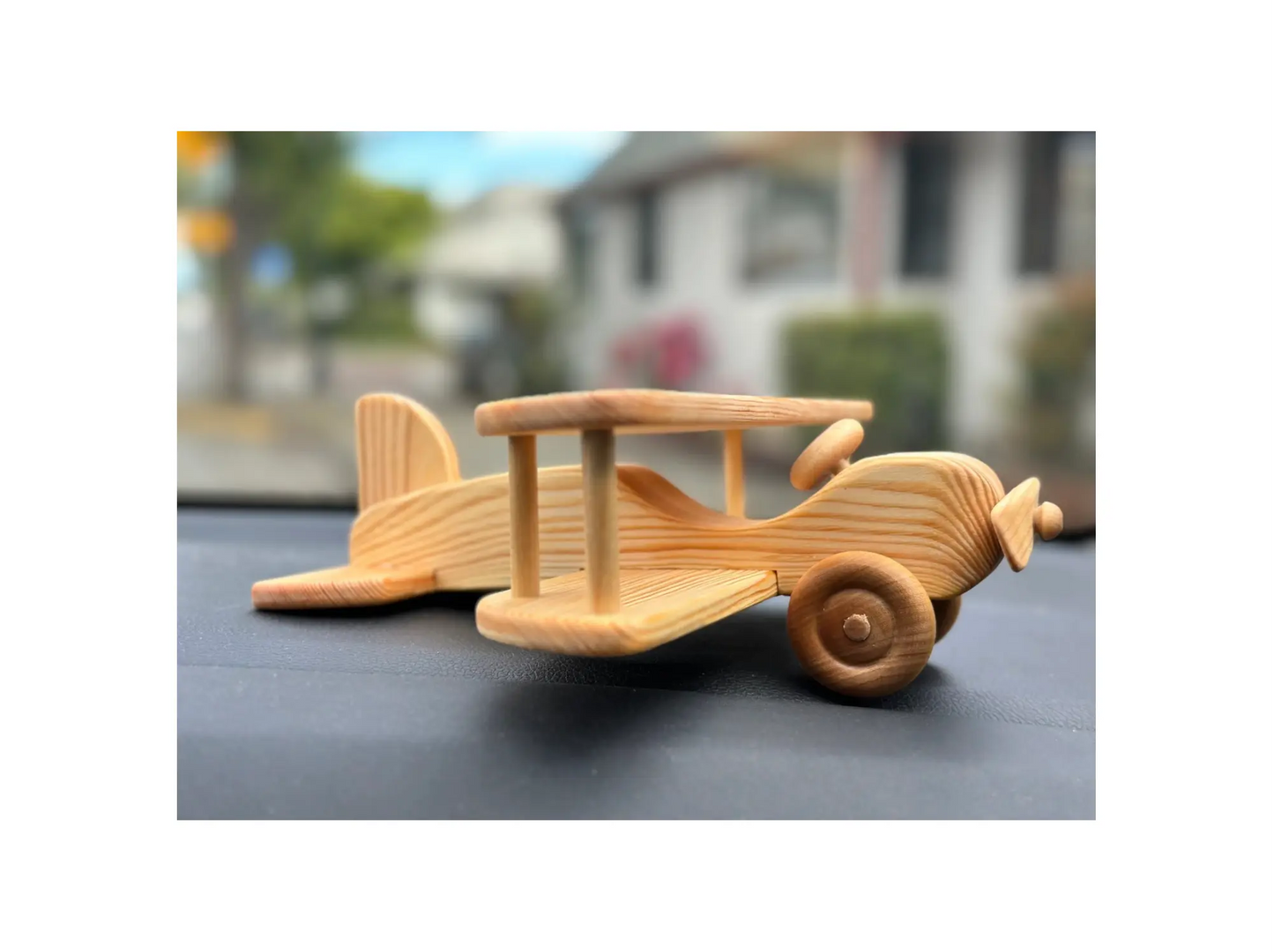 Wooden toy airplane resting on surface showing size, wheels, and handcrafted structure
