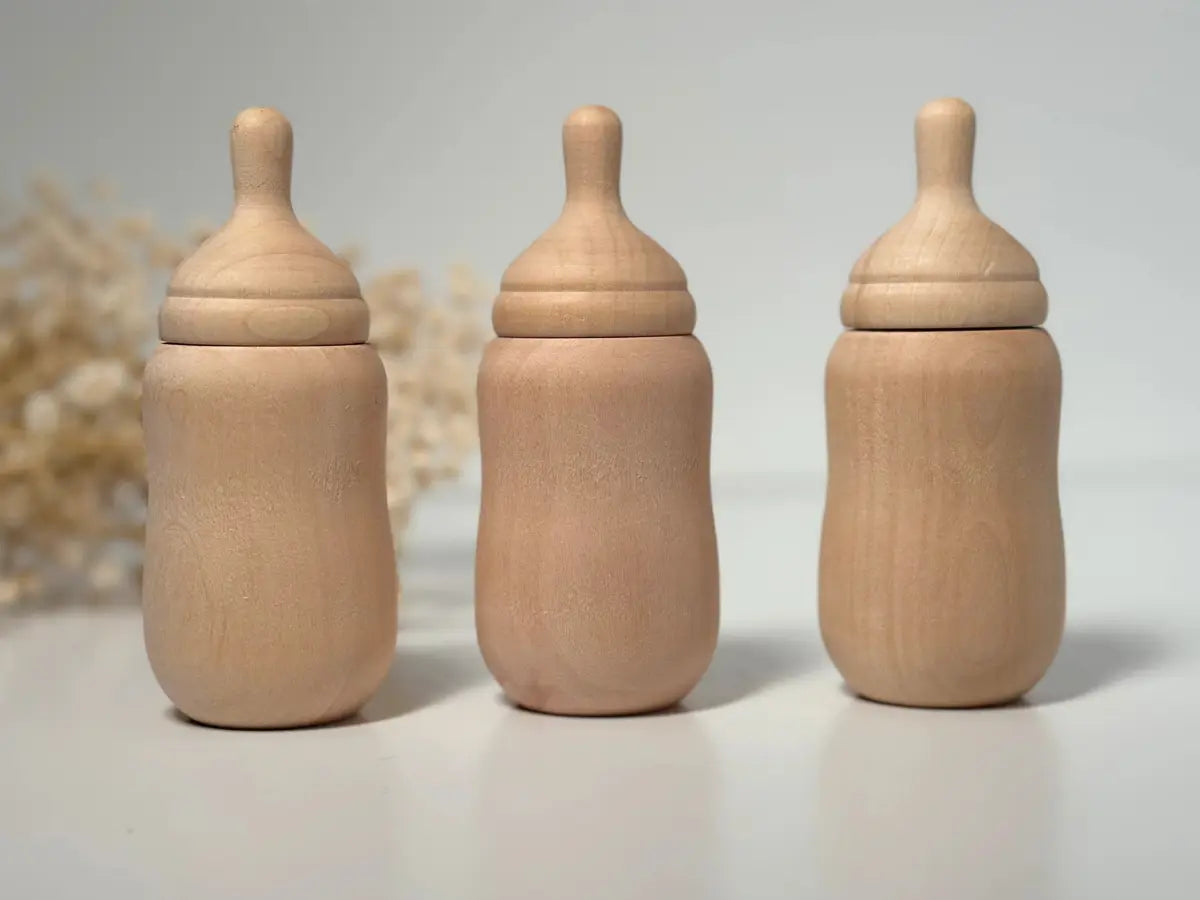 Three wooden baby bottle toys on a light background