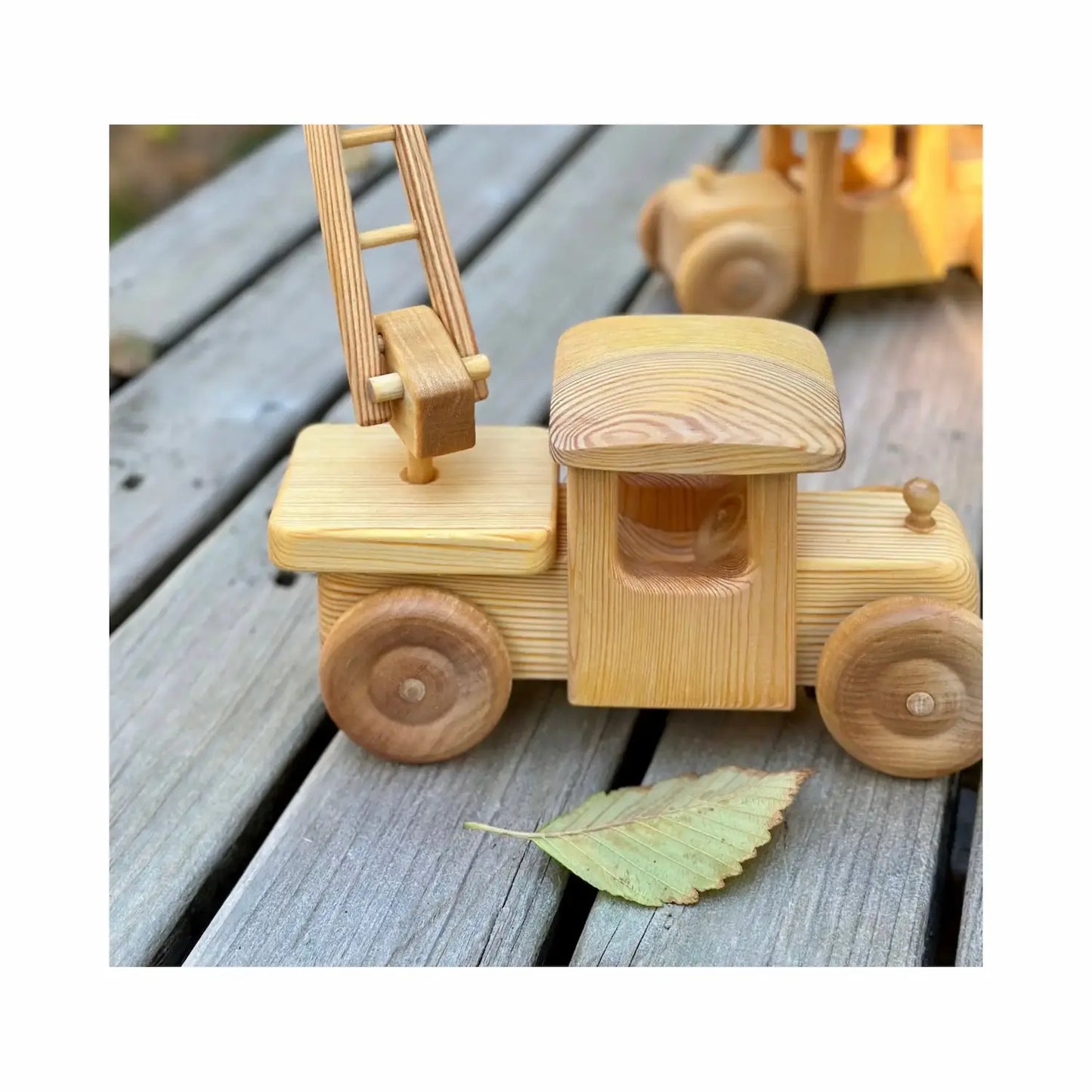 Detail of handcrafted wooden firetruck with movable ladder pivot showing natural wood construction