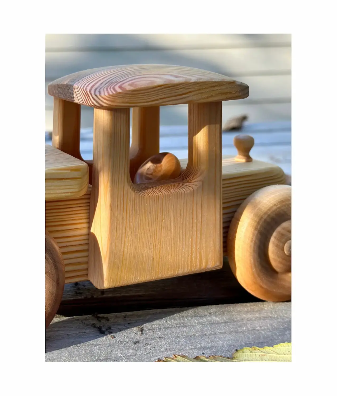 Detail of handcrafted wooden firetruck cab with small steering wheel and smooth natural wood finish