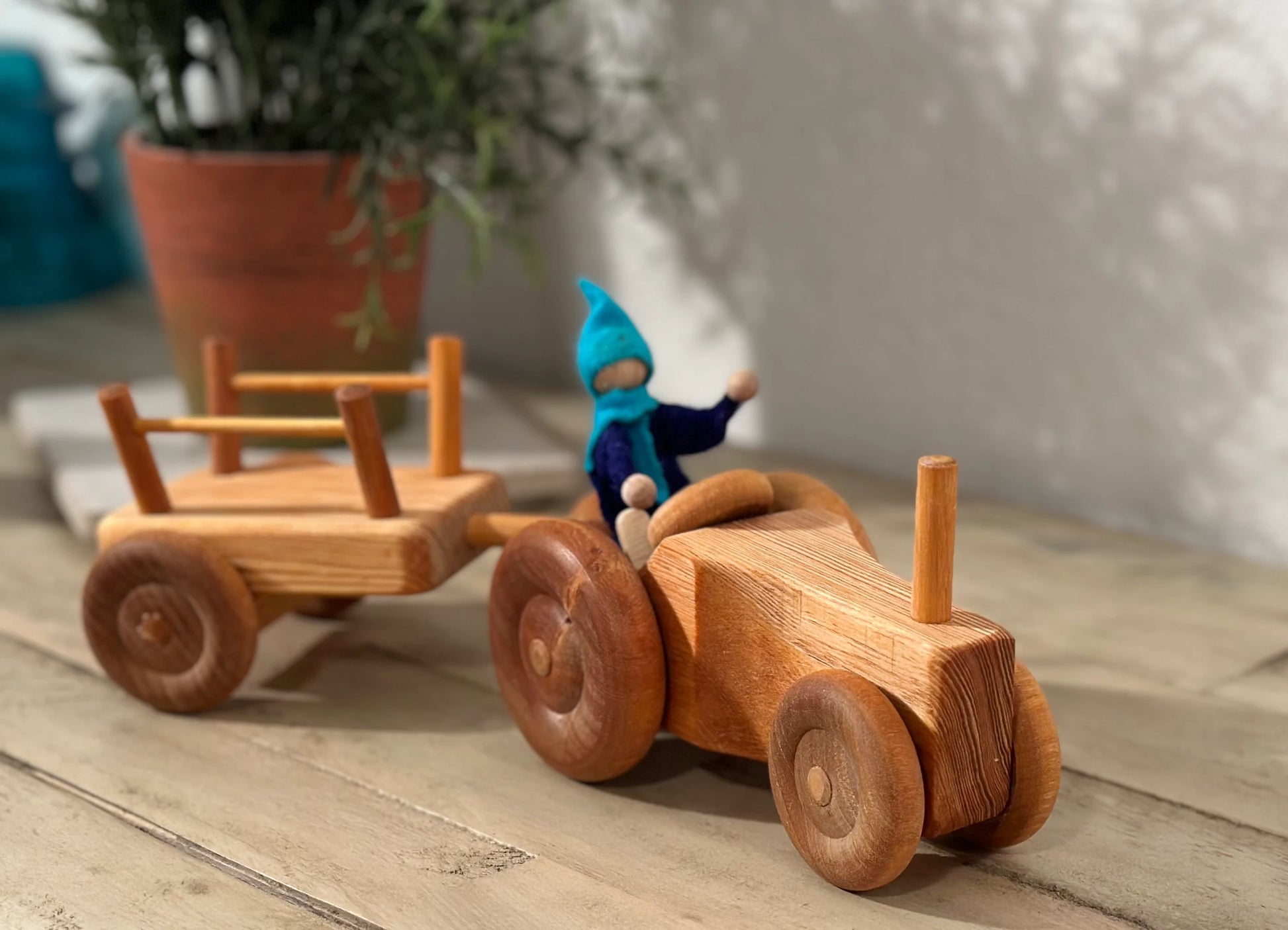 Wooden toy tractor with trailer in a small-world play scene carrying a figure