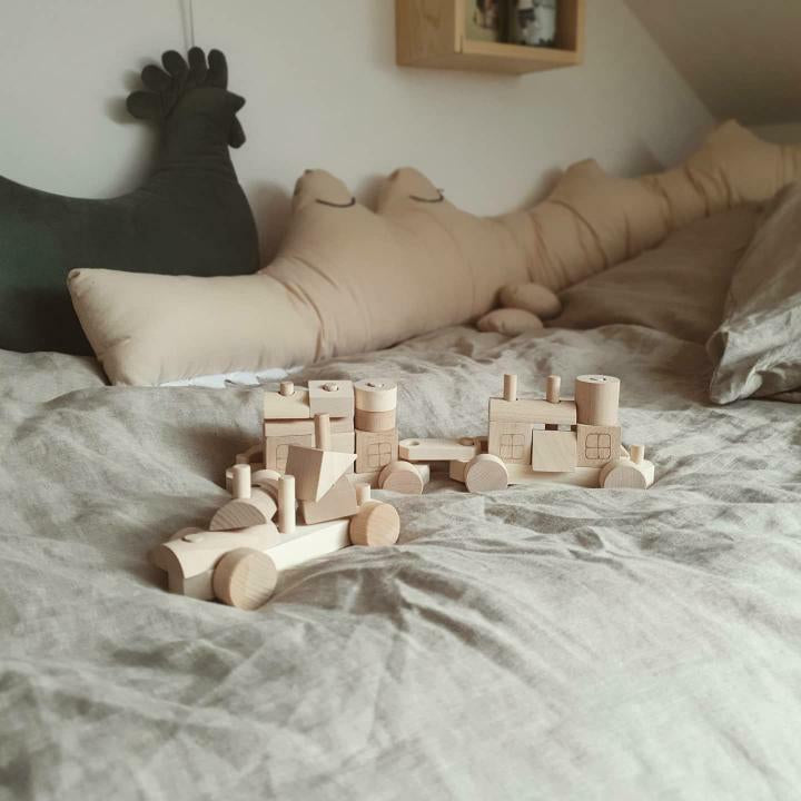 Natural wooden train and blocks arranged in a cozy child’s bedroom