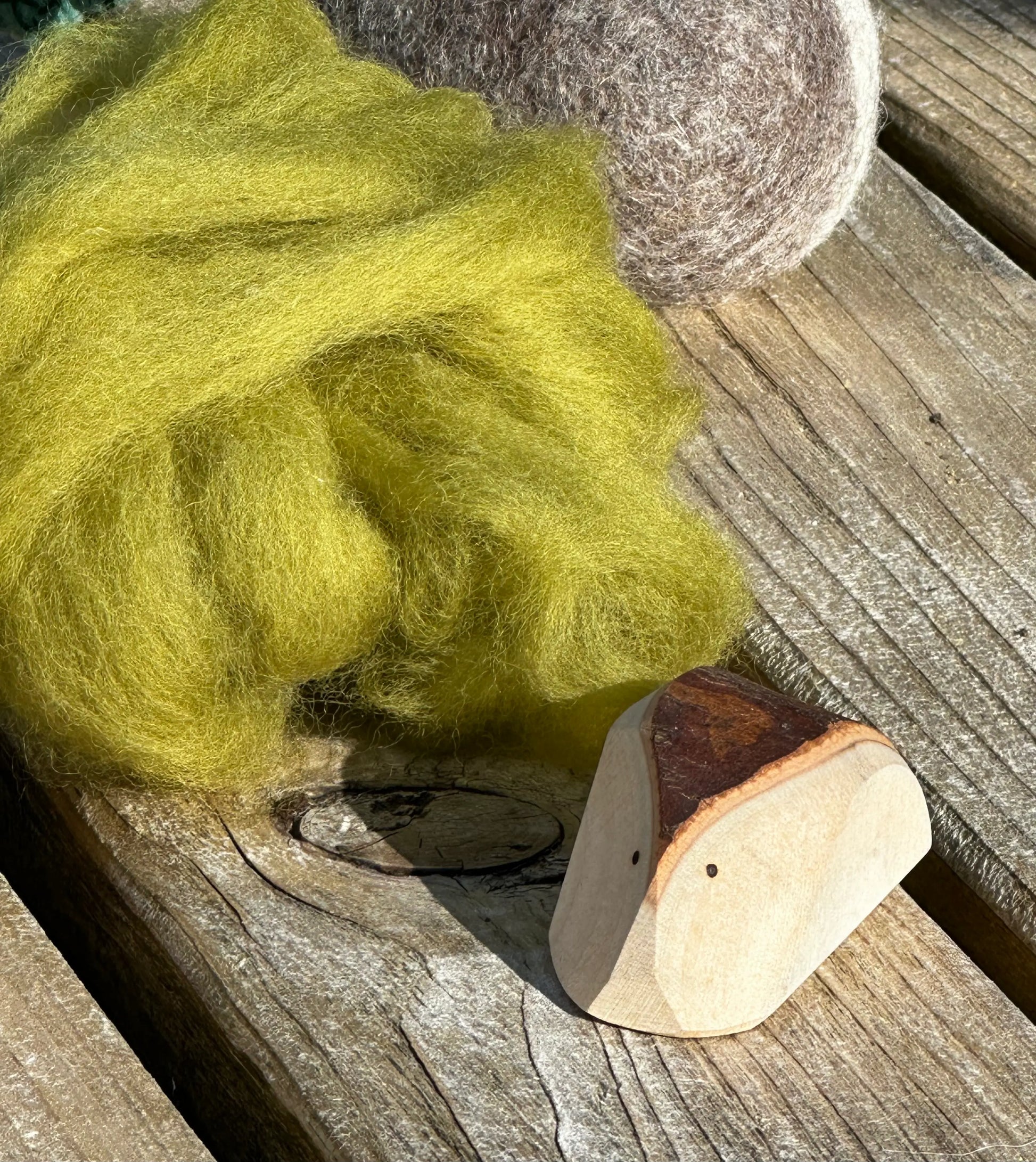 Wooden Tree Creatures arranged with green wool for nature table and sensory play
