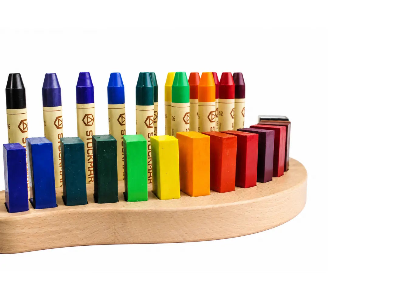 Set of colorful stick and block crayons on a wooden holder against a white background