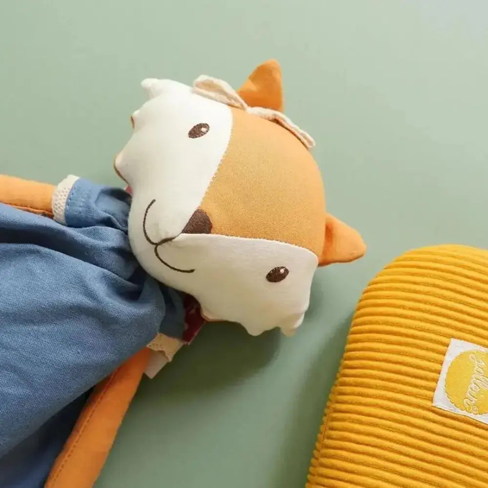 Plush soft woodland rag doll with a blue arm and yellow pillow on a light green background