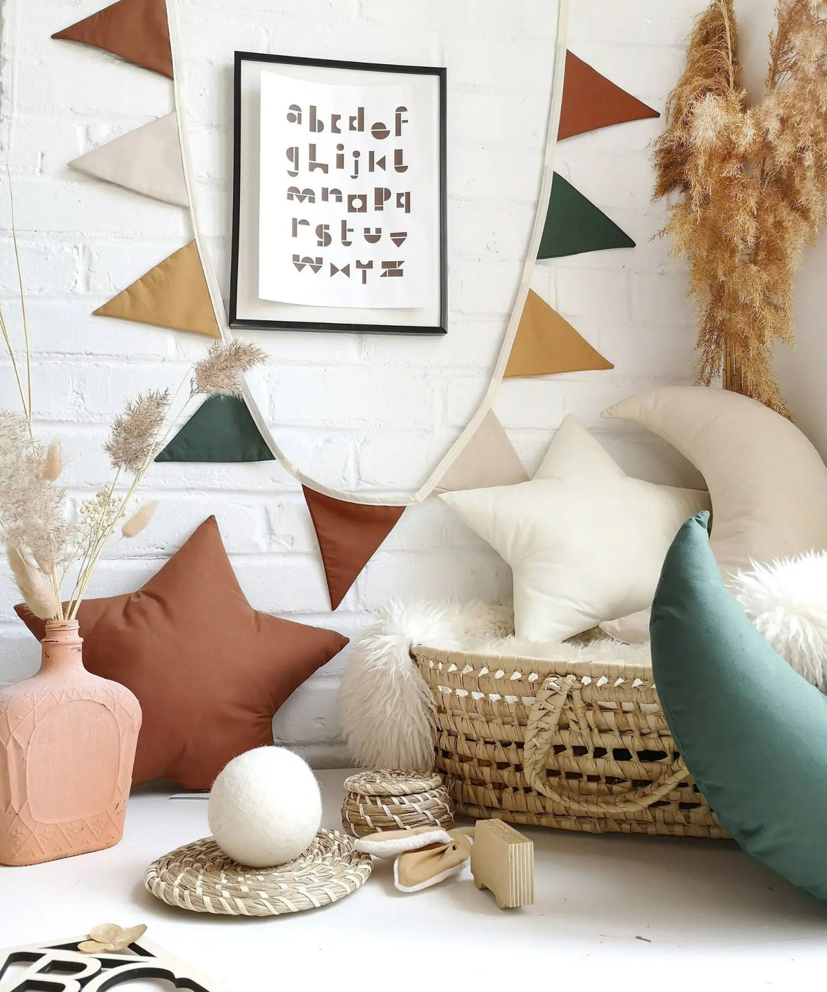 Woodland linen pennant garland in cinnamon, ivory, ochre and deep green hanging against a white brick wall