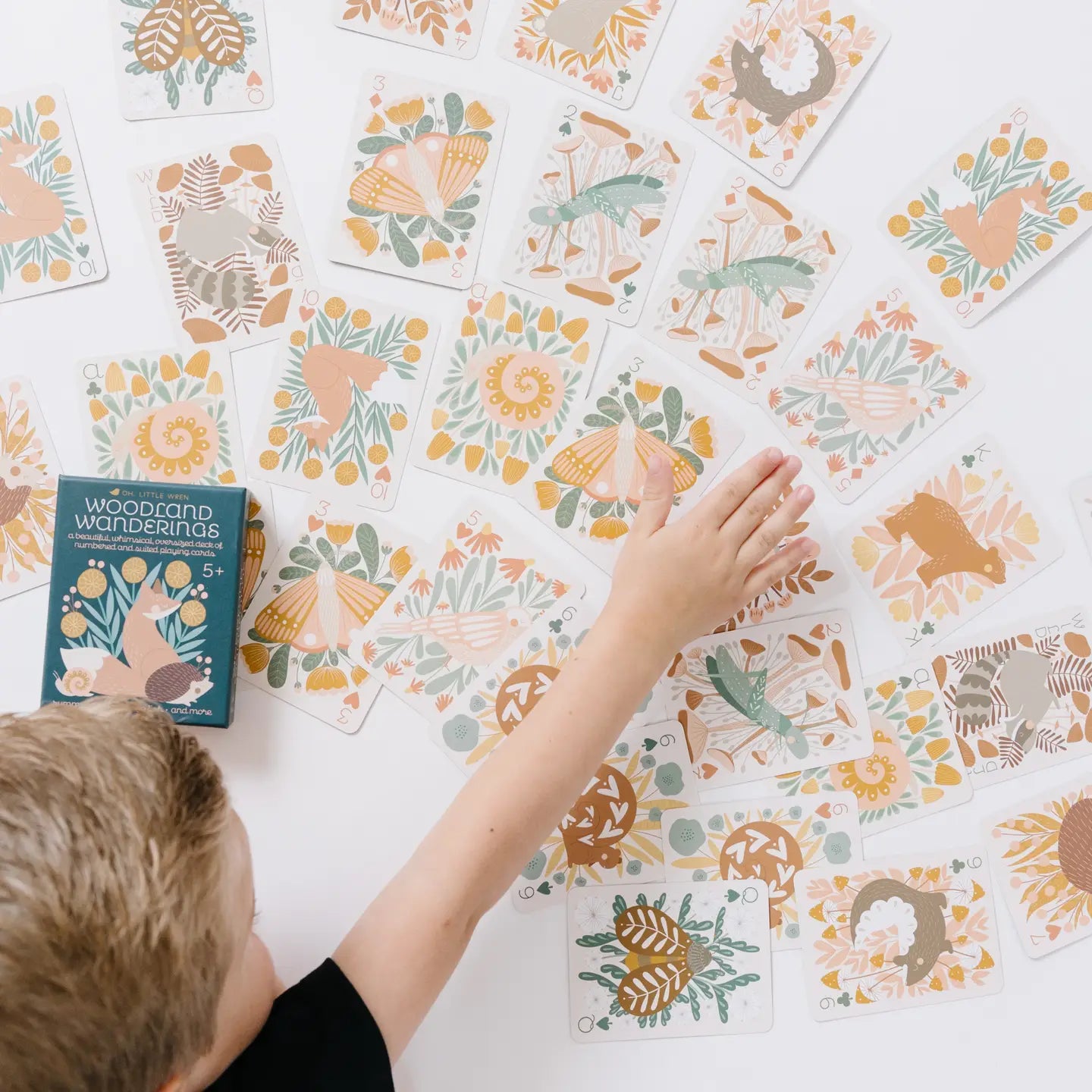 Woodland playing cards spread out on table with hand showing size