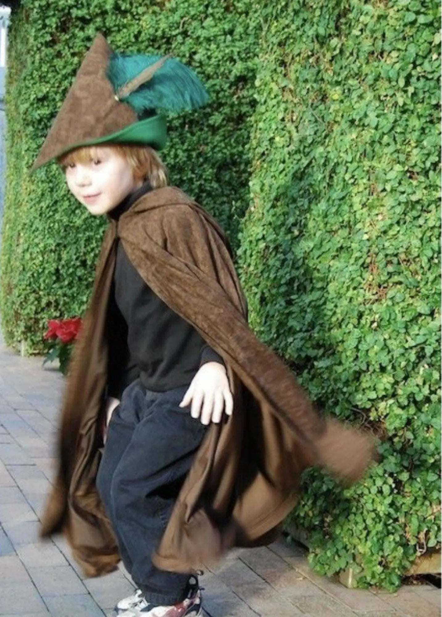 Child wearing woodsman cape outdoors for imaginative forest and adventure play