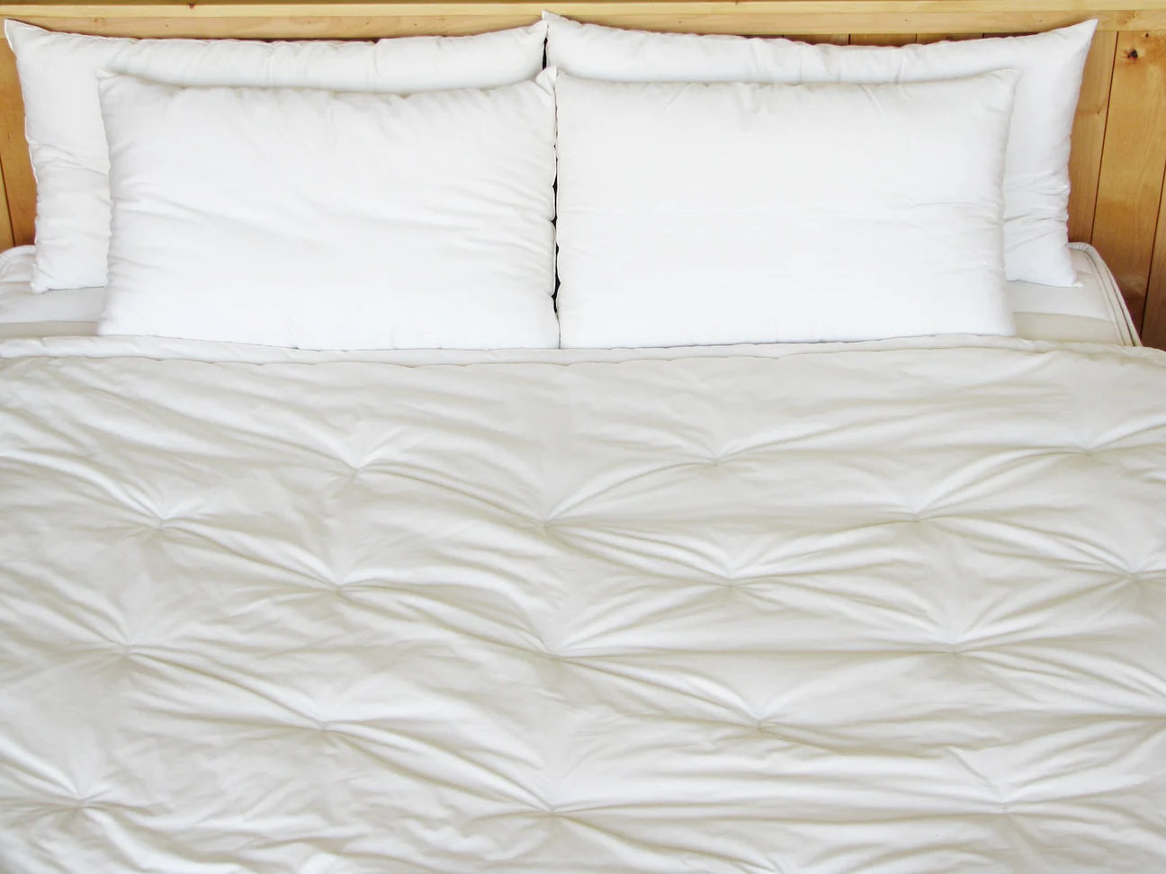 Quilted wool comforter spread across bed showing stitched pattern and even fill