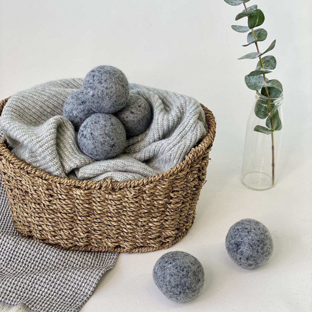 Gray wool dryer balls in wicker basket with eucalyptus