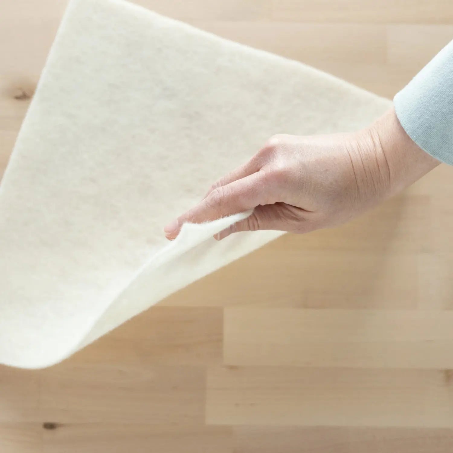 Wool prefelt with corner lifted to show thickness. 