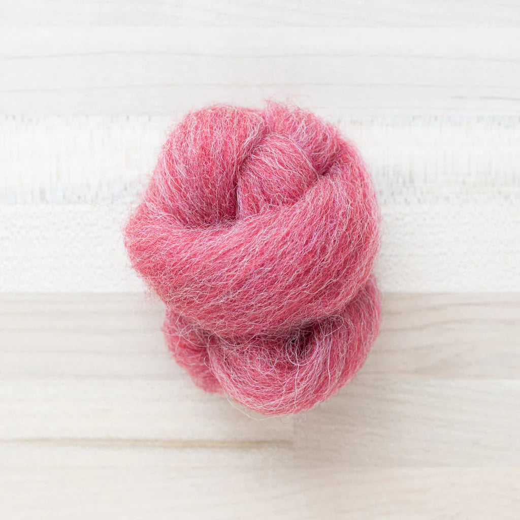 knot of heirloom radish wool roving for needle felting on a wooden background