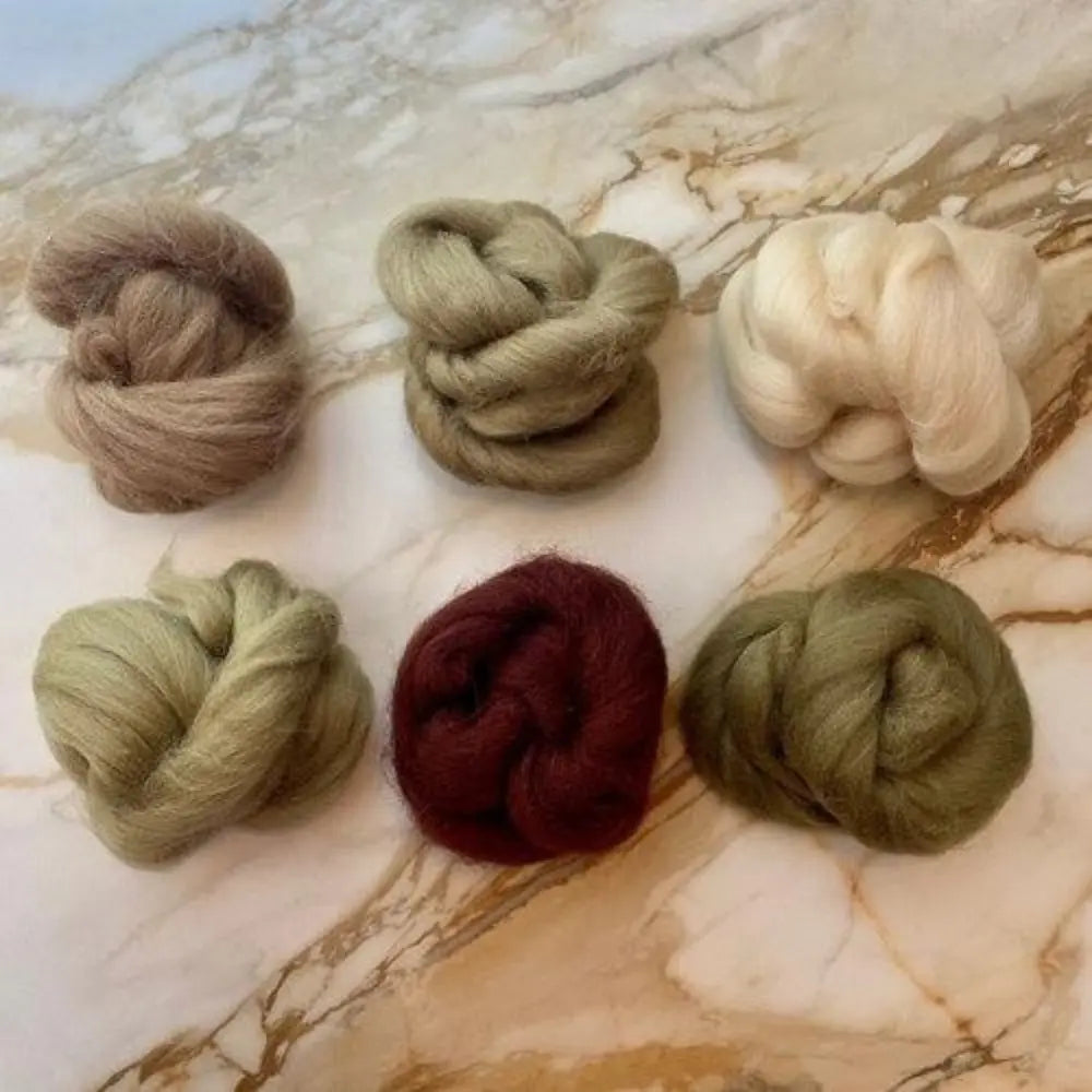 Set of six skeins of combed wool top in various earth tones on marble background